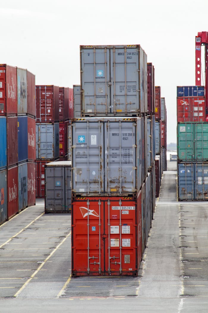 about-img-01 Vertical shot of colorful shipping containers stacked at an industrial port, showcasing logistics.